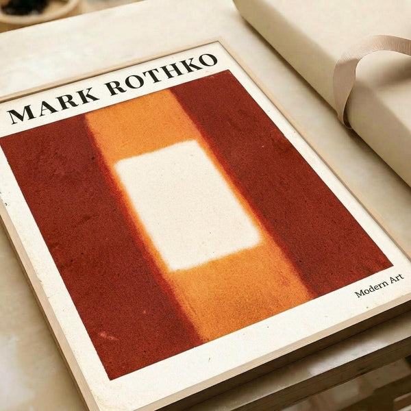 Abstract color field painting featuring a luminous white rectangular form centered on a warm gradient background transitioning from deep burgundy red through orange to golden yellow. The white shape appears to glow with soft, hazy edges that blend into the surrounding warm tones. Print displayed on cream paper with visible texture, lying flat alongside rolls of white paper in soft natural lighting.