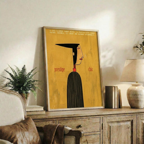 May include: Framed vintage-style poster with yellow background featuring stylized profile of woman in black dress with geometric design. French text at top reads about chic illuminating each detail. Words "prestige" and "chic" in red text. Poster displayed on rustic wooden sideboard alongside books, ceramic vase, and fern plant in neutral-toned living room setting.