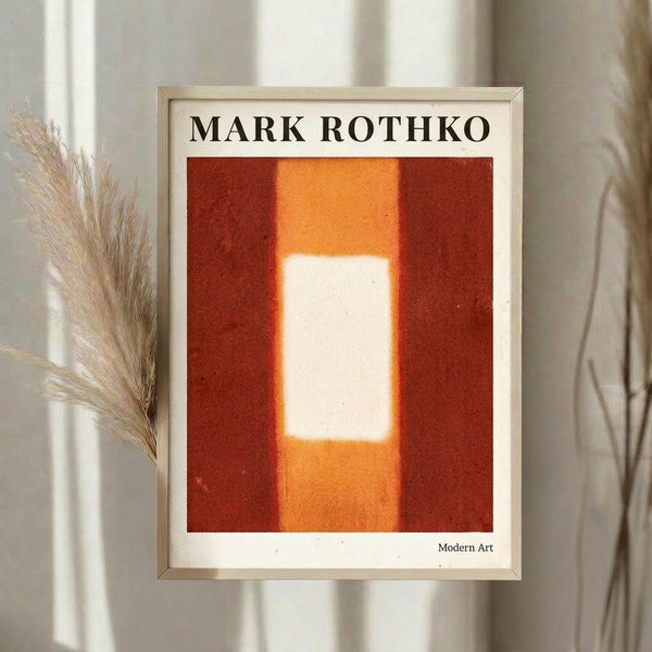 May include: Framed art print in light wood frame hanging on white wall next to dried pampas grass. Abstract painting features warm orange and red color blocks with glowing white rectangular center. Modern minimalist interior setting with natural lighting and neutral tones.