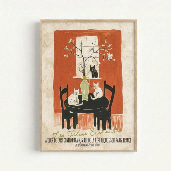 Framed vintage-style art print featuring an orange and cream interior scene with a black round table, chairs, and several cats - white and black cats positioned around a green vase with flowering branches near a window. Text in French appears at the bottom with Paris gallery information and 1996 date. The artwork has a warm, illustrated aesthetic with bold colors and is displayed in a light wood frame against a white wall.
