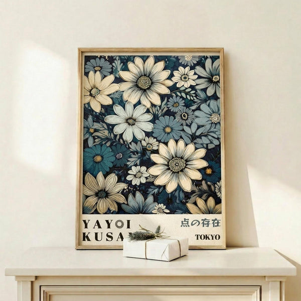 May include: Framed botanical art print featuring white and blue daisy-like flowers on dark navy background, displayed on light wood console table with small wrapped gift box. The poster shows "YAYOI KUSAMA" and Japanese characters with "TOKYO" text at bottom. Natural wood frame complements minimalist styling against cream wall with soft natural lighting.