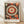May include: Framed modern art poster with large concentric circles in red, cream, and black, surrounded by abstract botanical patterns and geometric shapes. The artwork features intricate line work and dotted details in a folk art style. Text reads "Yayoi Kusama Japan 1945" below the main design. Light wood frame sits on wooden flooring against white wall with soft natural lighting.