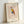 May include: Framed art print featuring a geometric owl in Picasso's minimalist style with colorful sections in red, yellow, blue, and orange against a beige background. The print shows "PICASSO" at top and "The Met L'art Minimaliste" at bottom. Light wood frame sits propped against white wall with soft natural lighting creating gentle shadows.