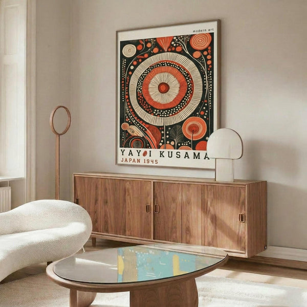 May include: Framed poster with vibrant orange and red circular patterns and geometric designs on dark background, displayed above wooden sideboard in modern living room with white curved chair, glass coffee table, and minimalist decor