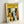May include: Framed poster print featuring stylized cats in various colors and patterns against a bright yellow background. The word "FELINES" appears at the top in black letters. Multiple cartoon-style cats are arranged in rows, including black, orange tabby, gray striped, and white cats with different facial expressions. The artwork has a mid-century modern illustration style with bold, flat colors. Natural wood frame sits against white wall with soft lighting creating shadows.