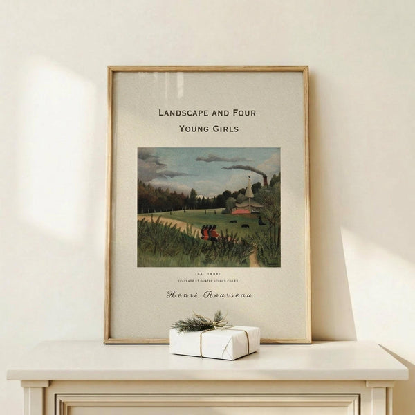 May include: Framed art print of Henri Rousseau's 1895 naive style landscape painting showing four young girls in red dresses walking through green countryside with industrial smokestacks in background, displayed on light wood console table next to small white gift box with twine and evergreen sprig against cream wall
