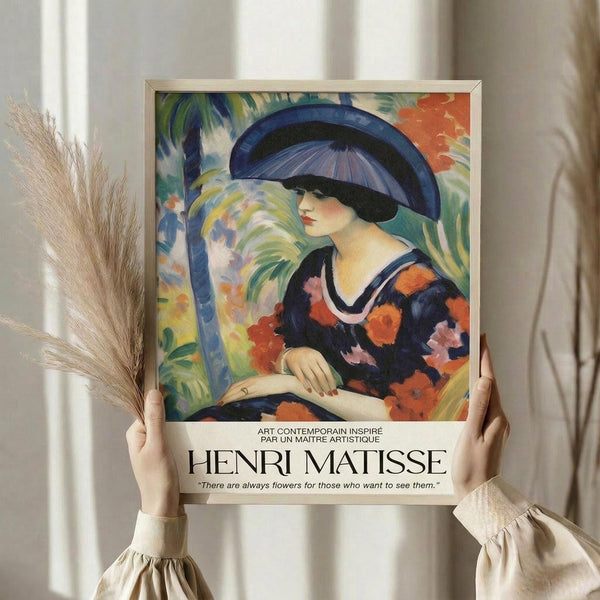 May include: Framed art poster featuring a woman in a wide-brimmed blue hat and floral dress in vibrant Fauve style with bold colors including oranges, blues, and greens. Person in beige clothing with ruffled sleeves holds the framed print alongside dried pampas grass against white curtained background. Quote about flowers appears below the artwork.