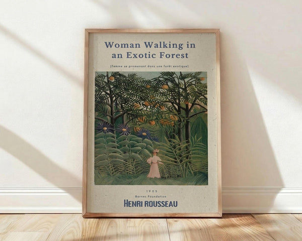 May include: Framed art print featuring Henri Rousseau's 1905 painting of a woman in pink dress walking through lush green jungle with exotic plants, flowers, and dense foliage. Natural wood frame against white wall on light wooden floor with soft shadows.