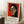 May include: Framed poster featuring a cubist-style portrait of a woman with geometric facial features, black hair, and earrings against a vibrant red background. The artwork shows angular, stylized proportions with bold colors including orange, green, and cream tones. French text appears below the image with an inspirational quote. The thin wooden frame leans against white paneled walls on a textured cream rug, with a coffee cup on a wooden block nearby.