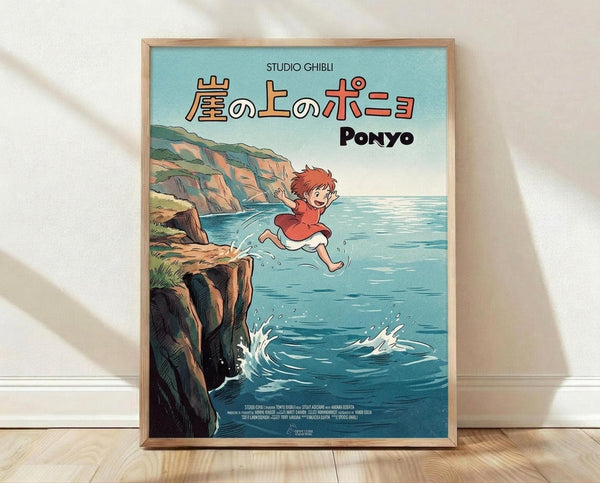 May include: Framed Studio Ghibli Ponyo movie poster in natural wood frame leaning against white wall on light wooden floor. The artwork shows red-haired Ponyo in orange dress jumping from rocky coastal cliffs into bright blue ocean water with splashing waves. Japanese text and "PONYO" appear at top against soft blue-green sky. Classic anime illustration style with warm earth tones contrasting against cool ocean blues.