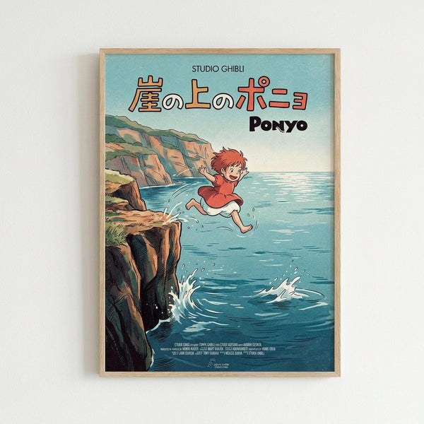 May include: Framed Studio Ghibli Ponyo movie poster print hanging on white wall in light wooden frame. Shows red-haired boy character jumping from rocky coastal cliff into bright blue ocean water with splash effects. Japanese text and "PONYO" title at top against turquoise sky background. Classic anime illustration style with detailed seaside landscape and film credits at bottom.