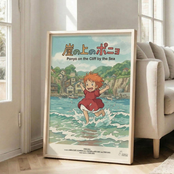 May include: Framed Studio Ghibli Ponyo poster displayed in bright living room with beige sofa and white walls. Artwork shows red-haired child character running through ocean waves with Japanese coastal village in background. Turquoise water, green hills, and traditional buildings create colorful anime-style illustration in light wood frame on wooden floor.