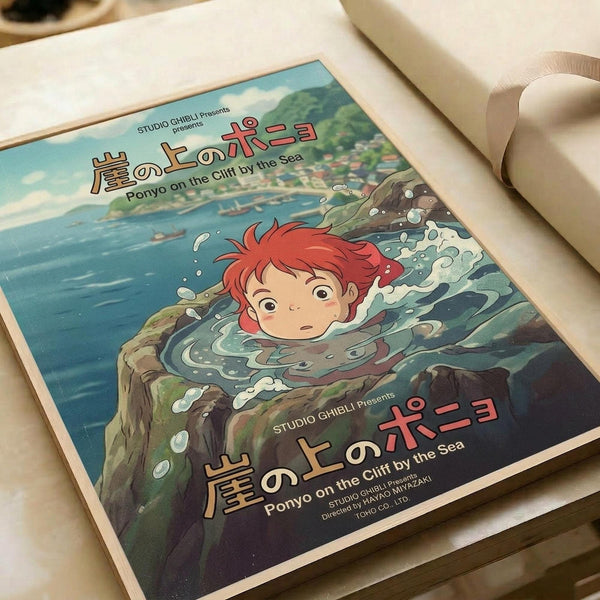Vintage-style Studio Ghibli movie poster featuring red-haired Ponyo character emerging from splashing ocean water near rocky cliffs. Japanese and English text displays "Ponyo on the Cliff by the Sea" with coastal village in background. Poster has weathered, aged appearance with muted blue and green tones. Print is placed on white surface next to rolled paper tubes, showing realistic scale and texture details.