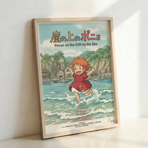 May include: Framed Studio Ghibli Ponyo movie poster in light wood frame leaning against white wall. Features young red-haired Ponyo in red dress running through ocean waves with coastal Japanese village and green hills in background. Bright anime art style with blue-green water, cloudy sky, and Japanese text above English title.