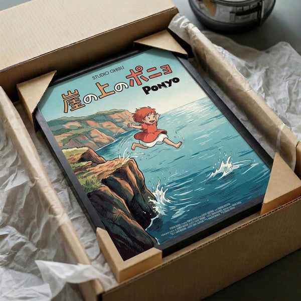 May include: Framed Studio Ghibli Ponyo poster showing red-haired character running across blue ocean waves near rocky coastal cliffs, packaged in cardboard shipping box with protective wrapping and wooden frame corners visible, photographed on white surface with partial view of dark objects in background