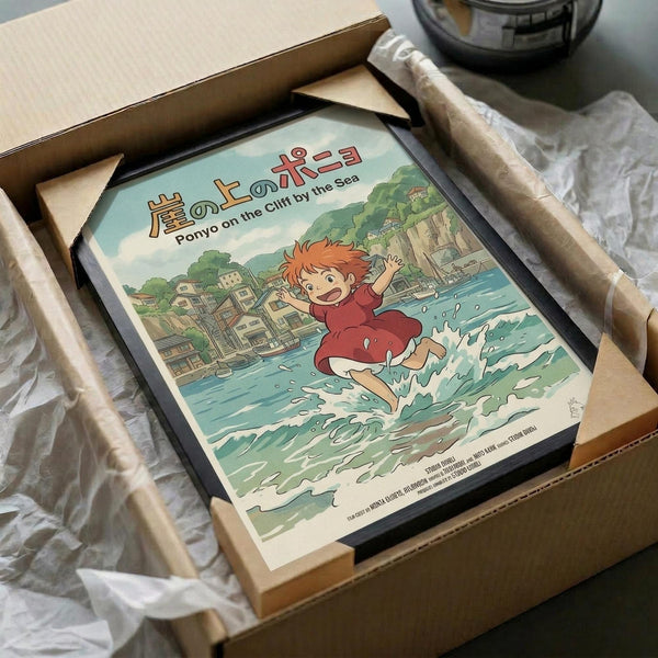 May include: Framed Studio Ghibli Ponyo poster in black frame, packaged in cardboard box with tissue paper. Artwork shows red-haired boy Ponyo running through ocean waves with coastal town and green cliffs in background. Japanese text at top reads "Ponyo on the Cliff by the Sea." Colorful anime illustration with turquoise water, traditional buildings, and lush vegetation. Frame sits in shipping materials on white surface.