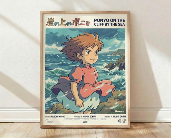 May include: Framed Studio Ghibli Ponyo movie poster in light wood frame leaning against white wall on wooden floor. Features anime-style illustration of young girl with flowing brown hair in red and blue dress sitting by turbulent ocean waves near rocky cliff. Soft natural lighting creates shadows on white textured wall. Poster shows Japanese text at top with English translation, ocean scene in blues and greens, and film credits at bottom.