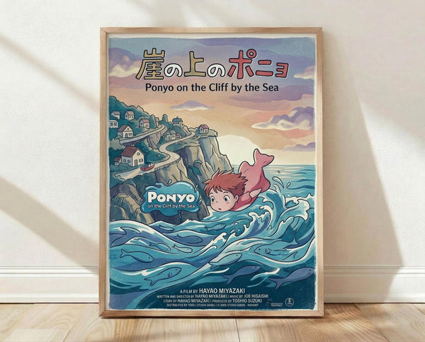 May include: Framed Studio Ghibli Ponyo movie poster print leaning against white wall on wooden floor. Shows red-haired character swimming in blue ocean waves with fish, clifftop village houses above, sunset sky. Japanese and English text at top. Natural wood frame, soft window light casting shadows on textured white wall.