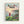 Framed poster featuring Studio Ghibli's animated art style showing a young girl with reddish hair in a red dress standing on a grassy cliff overlooking a coastal village. Below her are traditional Japanese houses with tiled roofs nestled along a curved bay filled with small fishing boats. The scene captures a sunset with soft pink and orange clouds over rolling hills. Japanese text appears at the top in colorful letters, with "PONYO" and "A FILM BY HAYAO MIYAZAKI" in black text below