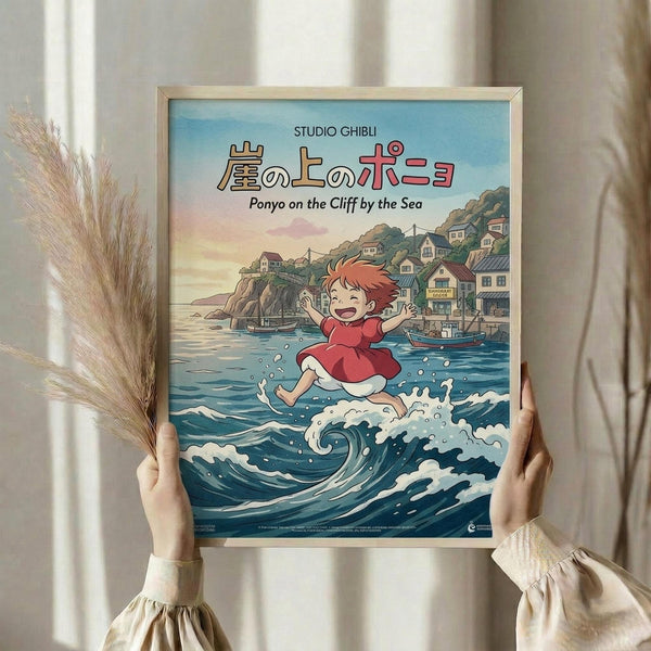 May include: Hands holding a framed Studio Ghibli Ponyo movie poster showing the red-haired character jumping over ocean waves with a coastal village in the background. The poster features Japanese text and "Ponyo on the Cliff by the Sea" subtitle. Scene shows dried pampas grass and cream curtains in soft natural lighting.