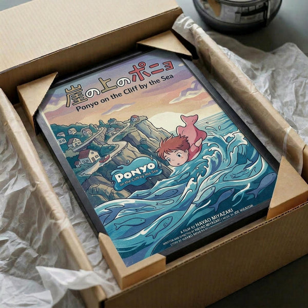 May include: Framed poster print in cardboard shipping box with protective packaging. Artwork shows anime-style character with red hair swimming in blue ocean waves near coastal cliff village. Japanese text at top with English subtitle "Ponyo on the Cliff by the Sea." Colorful illustration features sunset sky, traditional houses on rocky coastline, and dynamic water effects. Black frame against white tissue paper and brown cardboard packaging.