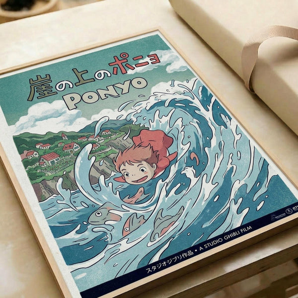 May include: Framed Studio Ghibli Ponyo poster print displayed on white bedding next to a cream pillow. The artwork shows red-haired Ponyo character surrounded by swirling blue ocean waves with a coastal village in the background. Japanese text appears at the top, with "Studio Ghibli Film" credited at bottom. Print has a light wooden frame and vintage-style illustration in teal, coral, and white tones.