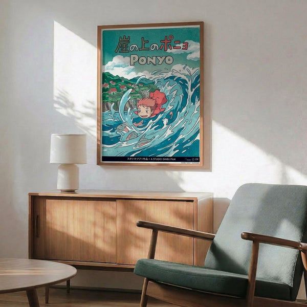 May include: A framed Studio Ghibli Ponyo poster displayed on a white wall above a mid-century modern wooden credenza. The poster features the red-haired character Ponyo swimming in blue ocean waves with a fish, set against a turquoise background with Japanese text. A teal upholstered armchair with wooden frame sits nearby alongside a small table lamp and round coffee table.