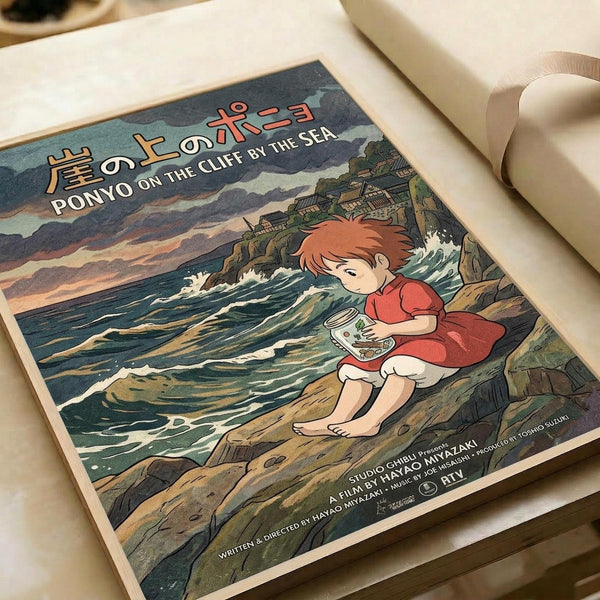 May include: Vintage-style poster print of animated character Ponyo sitting on rocky coastline holding a bowl, with crashing waves and clifftop village in background. Features Japanese and English text at top. Print shown on cream paper with rolled paper tube nearby on light wooden surface.