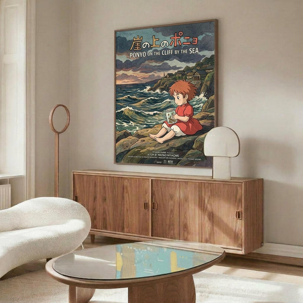 May include: Studio Ghibli Ponyo movie poster mounted above wooden sideboard in modern living room. Poster shows red-haired child character sitting on coastal rocks by turbulent ocean with Japanese and English text. White curved chair and glass coffee table visible in foreground. Warm wood tones throughout minimalist interior space.