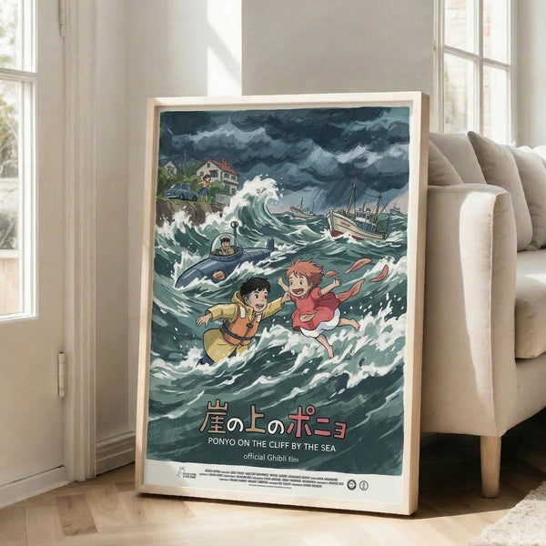 May include: Framed Studio Ghibli Ponyo movie poster displayed in bright living room corner next to beige sofa. Artwork shows two animated children floating in stormy ocean waves with dark clouds above, houses on clifftop, submarine and boats in turbulent green-blue water. Japanese and English text at bottom. Light wood frame, natural lighting from tall windows.