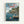 Framed Studio Ghibli-style poster featuring a coastal Japanese village scene with traditional wooden buildings on rocky cliffs overlooking blue water. A boy with green hair sits on a wooden dock looking down at a red-haired character floating in the water below. Multiple boats are moored in the harbor, with lush green trees covering the hillsides. The artwork has a painted, animated film aesthetic with soft blues and greens. Japanese text appears at the top in beige and red lettering, with "PONY