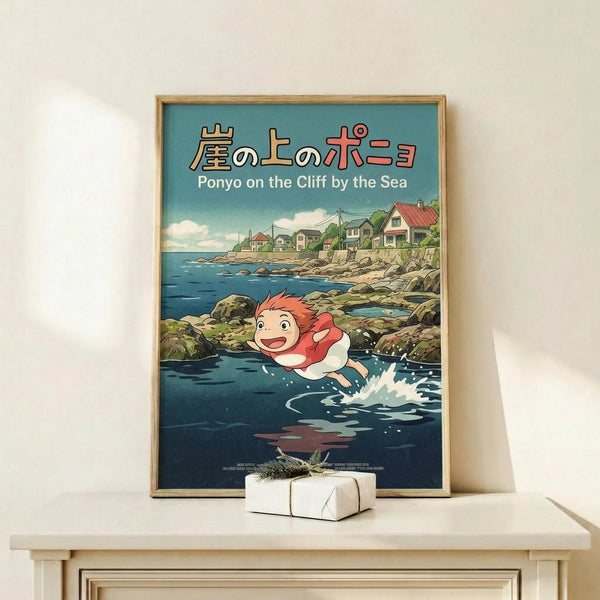 May include: Framed Studio Ghibli poster showing Ponyo, a red-haired fish girl character, swimming in dark blue ocean water near a rocky coastal village. The artwork features Japanese text at top with English subtitle "Ponyo on the Cliff by the Sea." Natural wood frame sits on light wooden shelf against white wall, with small wrapped gift box below.