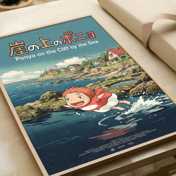 May include: Studio Ghibli-style poster print showing red-haired character Ponyo swimming in ocean waves near a rocky coastline with small houses on cliffs above. Features Japanese text at top with English subtitle. Vintage travel poster aesthetic with blue water, green landscape, and cloudy sky. Print displayed on white surface with rolled paper tube nearby, showing cream-colored border around artwork.