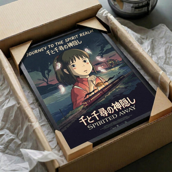 May include: Framed Spirited Away movie poster featuring young Chihiro in red shirt surrounded by white spirits against twilight landscape, displayed in cardboard shipping box with protective padding on neutral surface beside dark glass bowl