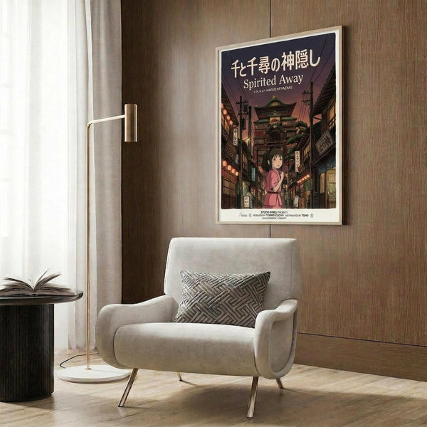 May include: Framed Spirited Away movie poster mounted on wood-paneled wall above modern cream armchair with geometric pillow. Poster shows young girl in pink outfit on traditional Japanese street with lanterns and buildings in twilight colors. Room features brass floor lamp, side table with open book, and neutral decor.