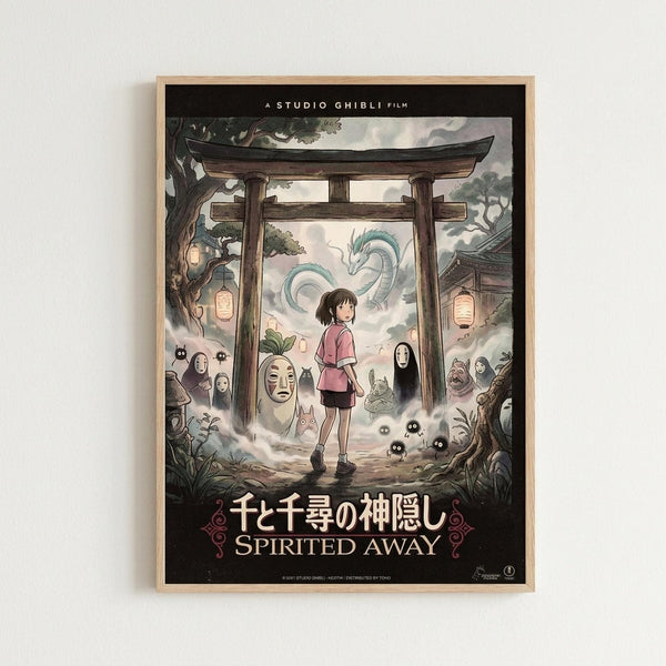 A framed Studio Ghibli Spirited Away movie poster featuring the young protagonist Chihiro in a pink shirt standing beneath a traditional Japanese torii gate. The artwork shows various spirit characters including No-Face, soot sprites, and a dragon in the cloudy sky background. The poster displays both Japanese and English text at the bottom against a black border, mounted in a light wood frame on a white wall.