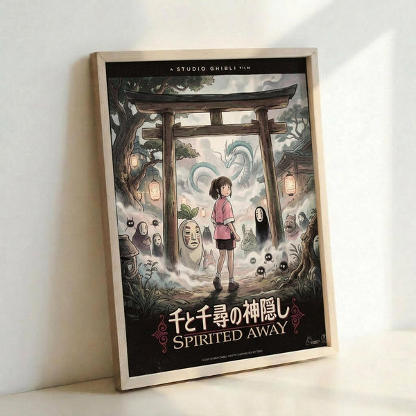 Framed poster of Studio Ghibli's Spirited Away featuring the main character Chihiro standing beneath a traditional Japanese torii gate. The artwork shows various spirit characters including No-Face, dragons, and magical creatures surrounding the young girl in a mystical forest setting with glowing lanterns. The poster displays both Japanese text and "SPIRITED AWAY" in English at the bottom, all contained within a light wooden frame leaning against a white wall.