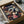 May include: Framed Spirited Away poster featuring Chihiro in pink outfit surrounded by colorful characters including No-Face, Haku the dragon, and bathhouse workers against a warm-toned background. Black frame sits in cardboard shipping box with white tissue paper padding on wooden surface.