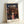 May include: Framed Spirited Away movie poster in light wood frame leaning against white wall. Features animated girl in pink top with Japanese bathhouse building behind her at twilight. Poster shows Japanese text at top with "SPIRITED AWAY" below in white letters. Rich sunset colors of orange, purple and deep blue create atmospheric background. Small production credits visible at bottom of poster.