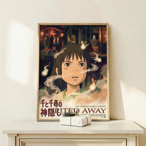 May include: Framed poster featuring animated girl with brown hair and green eyes surrounded by swirling white spirits, with colorful fantasy buildings in background. Japanese text and "SPIRITED AWAY" title at bottom. Wooden frame displayed on white shelf next to small wrapped gift box against cream wall.
