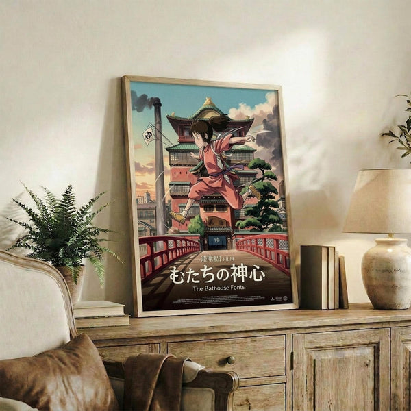 May include: Framed anime poster showing young girl in pink kimono leaping across traditional Japanese bathhouse with multi-tiered pagoda architecture, red bridge, and smokestack against cloudy sky. Japanese text at bottom. Displayed on rustic wooden console with books, ceramic vase, and fern plant in cozy living room setting with beige armchair.