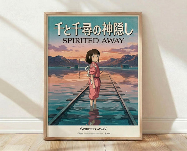 May include: Framed poster of anime character Chihiro from Spirited Away standing on flooded railway tracks. The young girl wears a pink outfit and looks back over her shoulder. Behind her stretches a dreamlike landscape with mountains, turquoise water, and sunset sky in soft pastels. Japanese and English text at top reads "Spirited Away." Light wooden frame sits on polished floor against white wall with soft shadows.