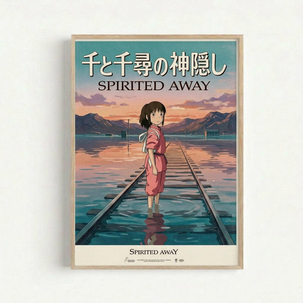Framed poster featuring animated character Chihiro from Studio Ghibli's film, standing on flooded railway tracks at sunset. The young girl wears a pink striped shirt and red shorts, looking over her shoulder. Background shows mountains, water, and a dramatic orange-purple sky. Japanese text and "Spirited Away" appear at top. Light wooden frame against white wall.