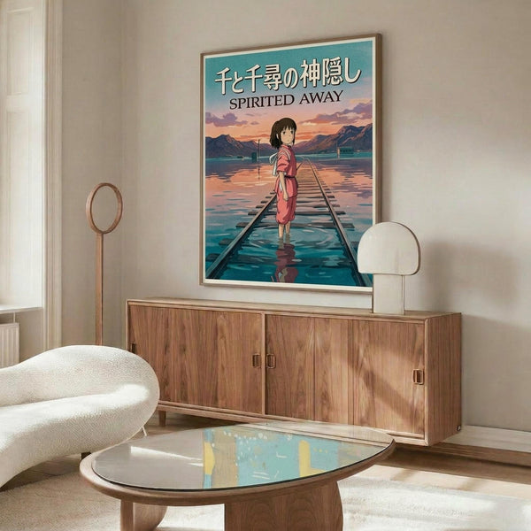 May include: Spirited Away movie poster mockup in modern living room setting with wooden sideboard, white upholstered chair, glass coffee table, and white table lamp. Poster shows anime character Chihiro in pink dress standing on flooded railway tracks with mountains and sunset sky in background. Japanese and English text at top. Warm wood tones throughout room with cream walls and natural lighting.