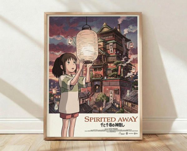May include: Framed Spirited Away movie poster showing Chihiro holding a white paper lantern against a backdrop of the magical bathhouse with traditional Japanese architecture, displayed in a light wood frame leaning against a white wall on wooden flooring with natural lighting casting shadows across the scene.