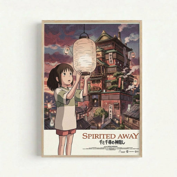 May include: A framed poster displaying anime-style artwork of a young girl with short black hair holding a white paper lantern. Behind her rises a fantastical multi-story bathhouse with traditional Japanese architecture, wooden balconies, and glowing lanterns. The scene features a dramatic sunset sky in purple and pink hues. The poster shows "Spirited Away" title text and Japanese characters at the bottom, all within a light wooden frame against a white wall.