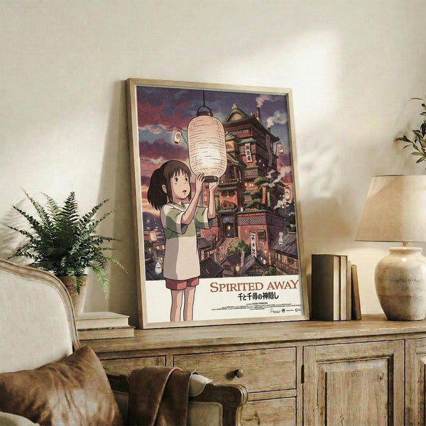 May include: Framed Spirited Away movie poster featuring Chihiro holding a white paper lantern against a backdrop of the elaborate bathhouse building with purple twilight sky. The poster sits on a rustic wooden sideboard alongside books, a ceramic vase, and fern plant in a cozy living room with cream armchair and warm lighting.