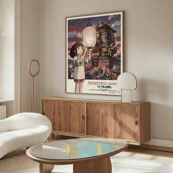 May include: Framed Spirited Away movie poster featuring Chihiro holding a paper lantern against a backdrop of the magical bathhouse, displayed above a mid-century modern walnut credenza in a minimalist living room with cream walls, white upholstered chair, and glass coffee table with colorful abstract art reflection.