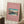 May include: Framed Japanese woodblock print poster featuring Mt. Fuji with snow-capped peak rising above a winter landscape with bare trees and a bridge over blue water, displayed against white paneled wall on white shag rug next to wooden side table with white coffee cup and cream-colored blanket