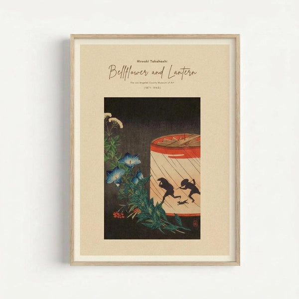 May include: Framed vintage Japanese woodblock print featuring blue morning glory flowers and foliage on the left side, with a red paper lantern on the right showing silhouettes of two small birds perched inside. The artwork has a dark background and is displayed in a light wooden frame with cream matting against a white wall.